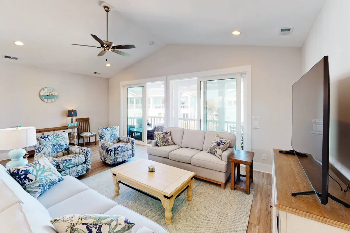 A cozy living room setup with a large, plush sofa, decorative chairs, a modern coffee table, and a mounted TV. The atmosphere is casual, inviting, and ideal for movie nights or group relaxation.