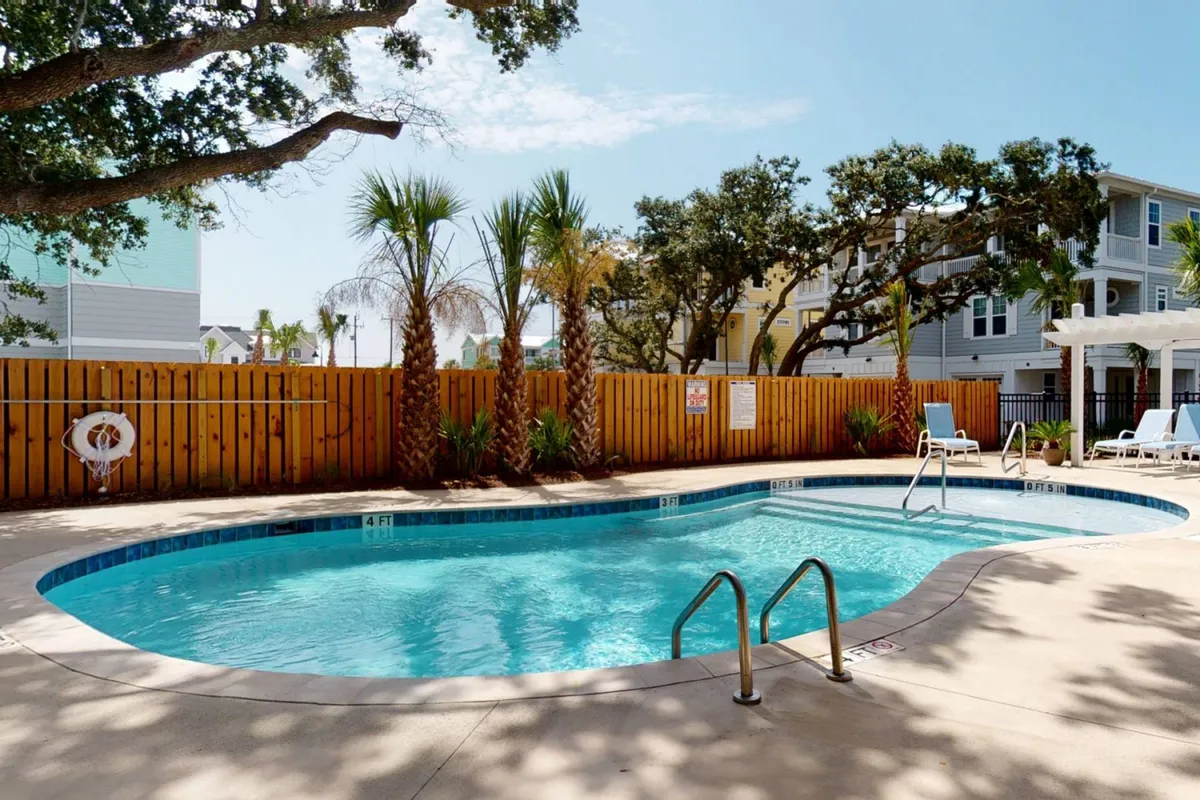 A sparkling pool surrounded by palm trees, loungers, and a spacious deck area, evoking a serene resort ambiance. The setting suggests opportunities for both active and leisurely poolside experiences.