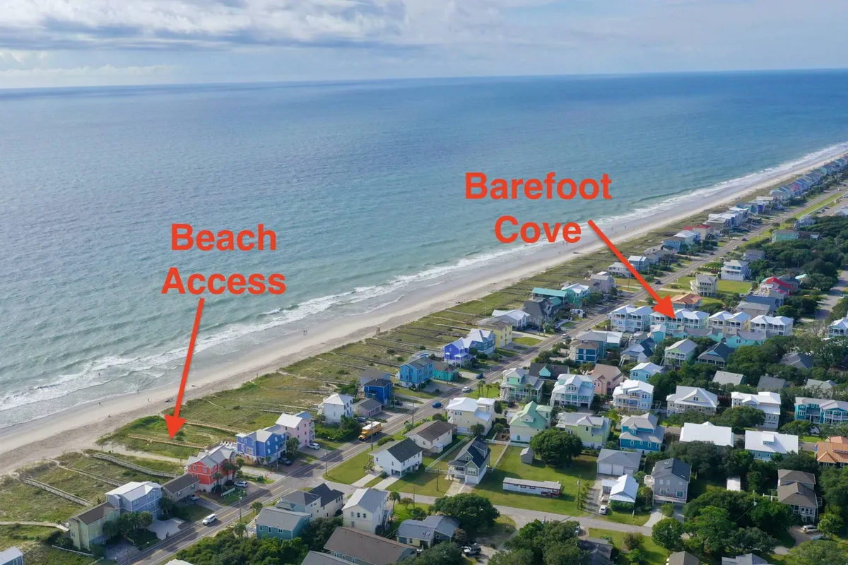 This exterior image shows the main entrance to Barefoot Cove with easy beach access, coastal homes, and a relaxed atmosphere. The walkway to the sand hints at the simplicity of reaching the ocean and sets the scene for a quintessential beach adventure. The image radiates a welcoming vibe, capturing the essence of effortless seaside living for all ages.